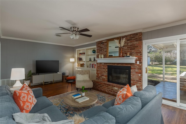 living area with a fireplace, crown molding, and wood finished floors