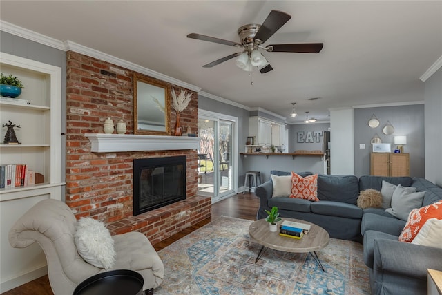 living area with built in shelves, a fireplace, ornamental molding, ceiling fan, and wood finished floors