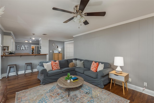 living area with ornamental molding, wood finished floors, a ceiling fan, and baseboards