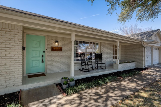 entrance to property with a garage, a porch, and brick siding