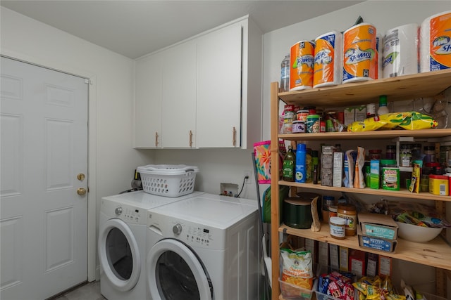 clothes washing area featuring washing machine and dryer and cabinet space