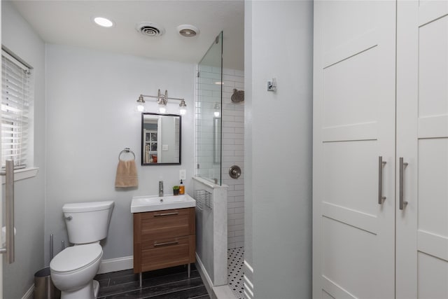 bathroom with baseboards, visible vents, toilet, walk in shower, and vanity