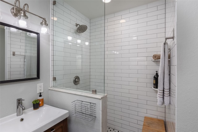 bathroom with a textured wall, a walk in shower, and vanity