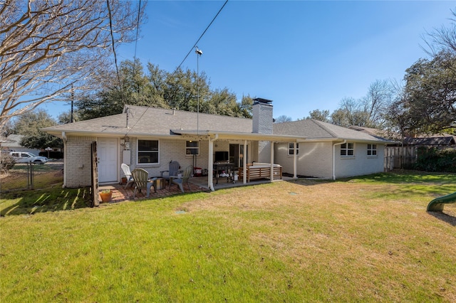 rear view of property with a lawn, a chimney, fence, a patio area, and brick siding