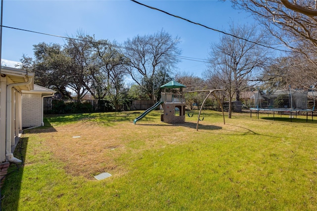 view of yard with a trampoline, a playground, and fence