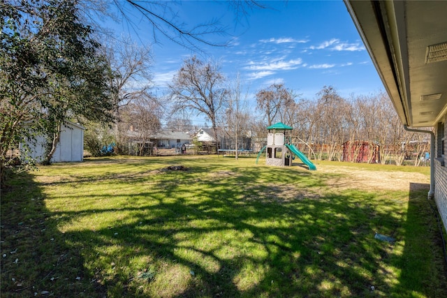 view of yard with a trampoline, a playground, and an outdoor structure