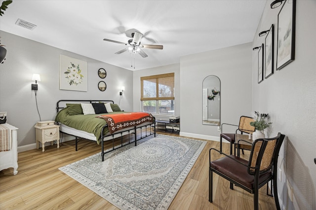 bedroom with baseboards, visible vents, and wood finished floors