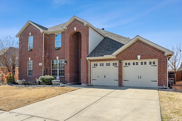 traditional home featuring concrete driveway, a shingled roof, an attached garage, and brick siding