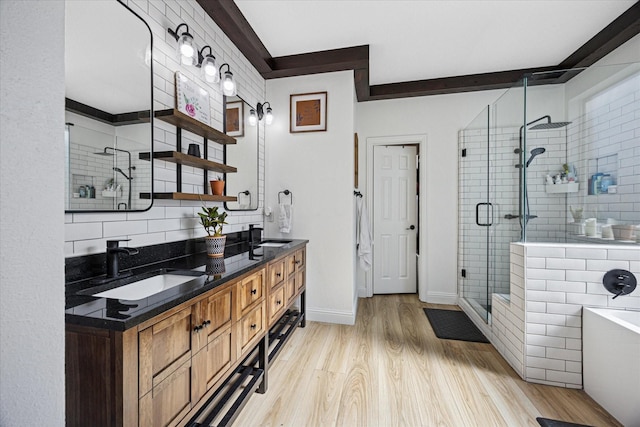 full bath featuring double vanity, a bathing tub, a sink, a shower stall, and wood finished floors