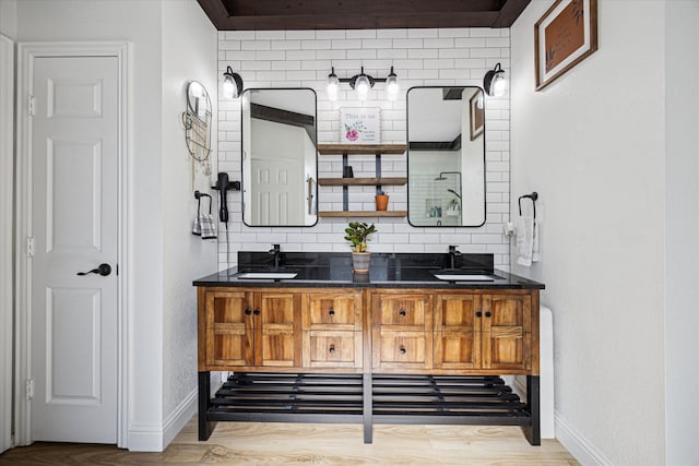 bathroom featuring tiled shower, a sink, decorative backsplash, and double vanity