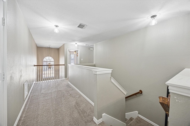 corridor with visible vents, carpet flooring, an upstairs landing, and baseboards