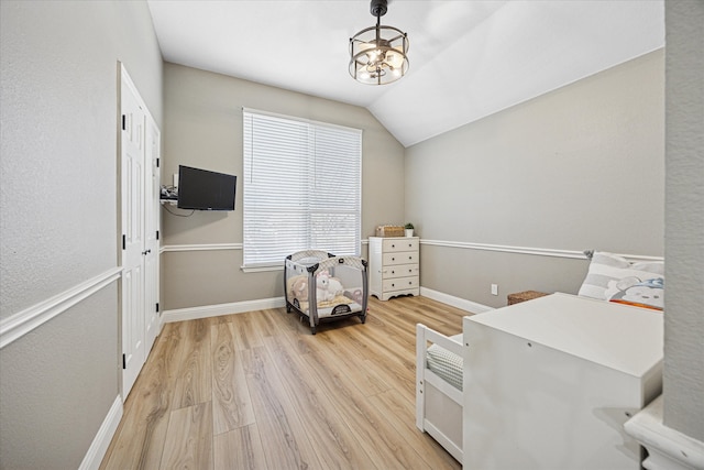 interior space featuring vaulted ceiling, light wood-style flooring, and baseboards