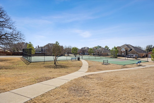 view of home's community with a tennis court, a residential view, fence, and a lawn