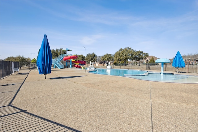 pool with a patio, a water slide, playground community, fence, and a water play area