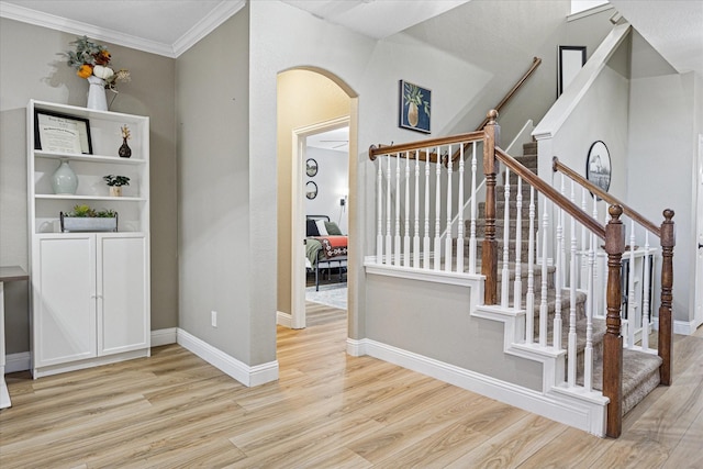 entryway with ornamental molding, arched walkways, baseboards, and wood finished floors