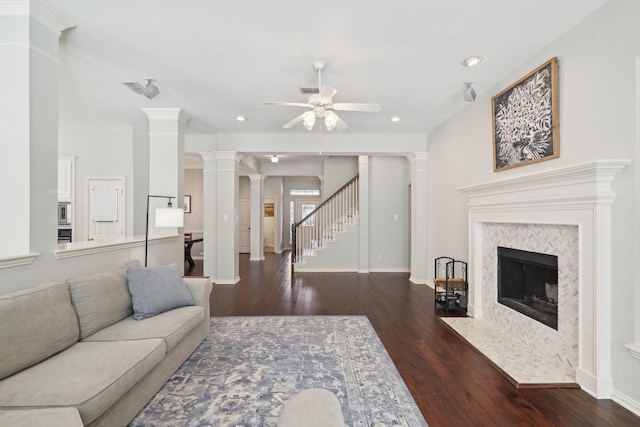 living room featuring decorative columns, a ceiling fan, stairway, wood finished floors, and a fireplace