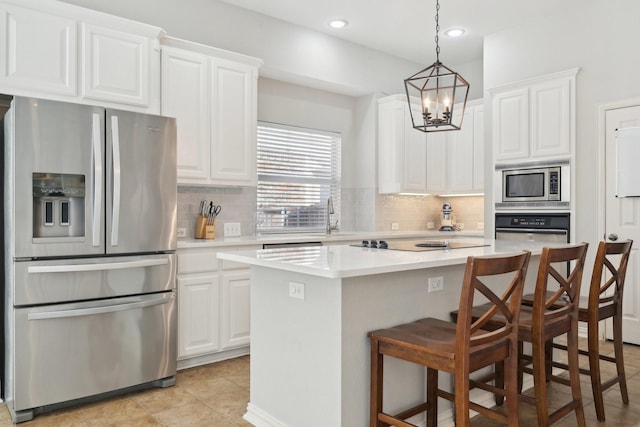 kitchen with tasteful backsplash, white cabinets, a kitchen island, stainless steel appliances, and light countertops