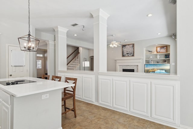 kitchen featuring built in shelves, decorative columns, visible vents, open floor plan, and a kitchen breakfast bar