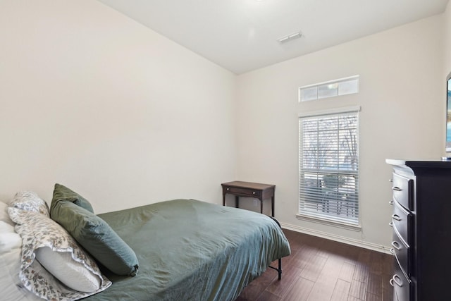 bedroom with visible vents, dark wood finished floors, and baseboards