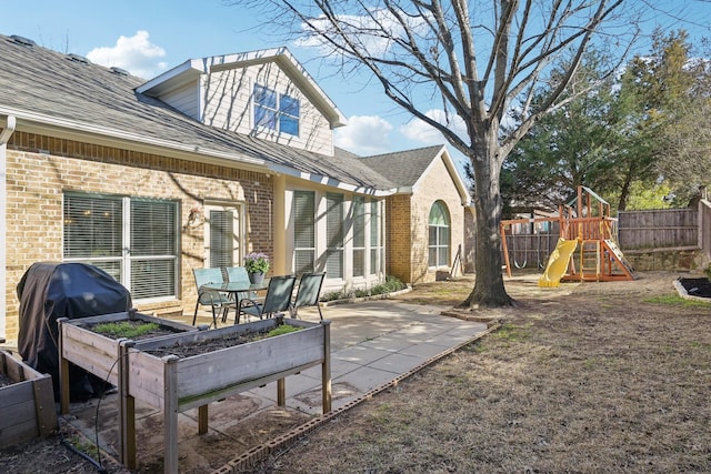 view of patio / terrace featuring a garden, fence, and a playground