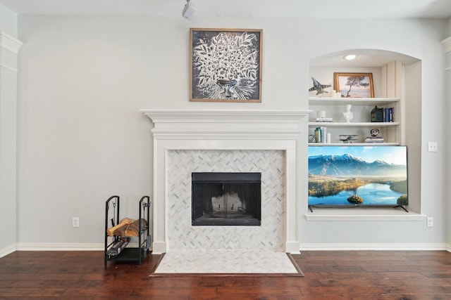 living room featuring baseboards, a tiled fireplace, and hardwood / wood-style floors