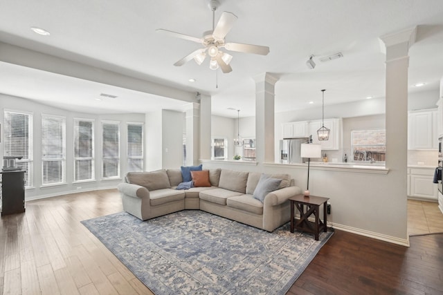 living area featuring ornate columns, visible vents, and wood finished floors