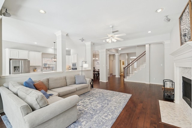 living area with recessed lighting, dark wood finished floors, a high end fireplace, and ornate columns