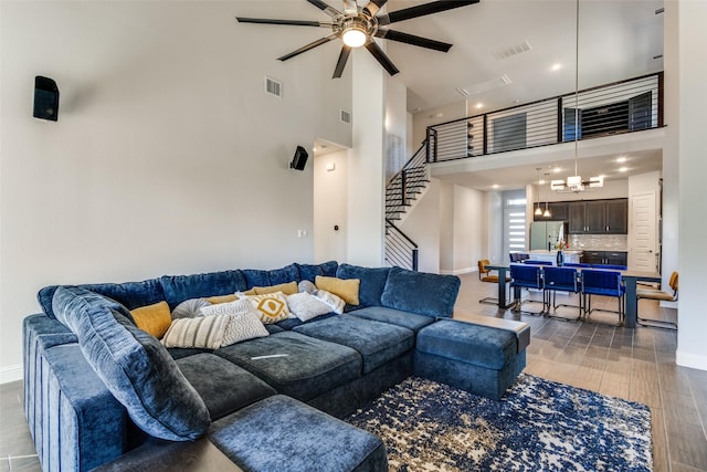 living area featuring a towering ceiling, visible vents, stairway, and baseboards