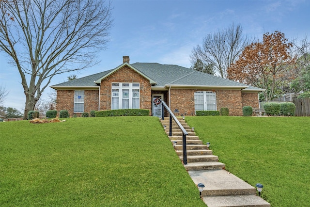 single story home featuring a shingled roof, a chimney, fence, a front yard, and brick siding