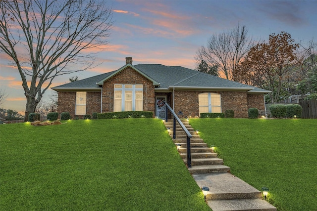 single story home featuring a chimney, roof with shingles, fence, a front yard, and brick siding