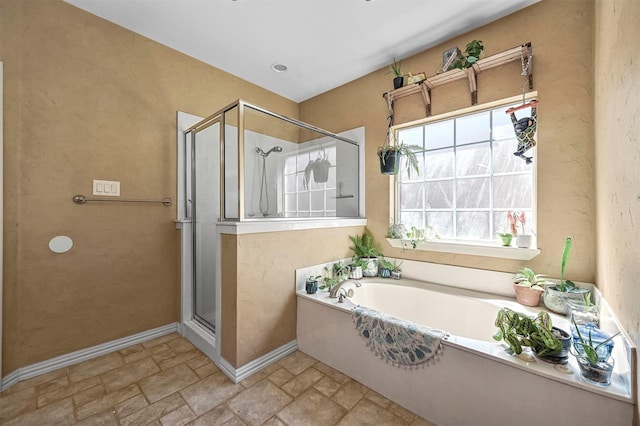 full bathroom featuring stone tile flooring, a shower stall, baseboards, and a bath