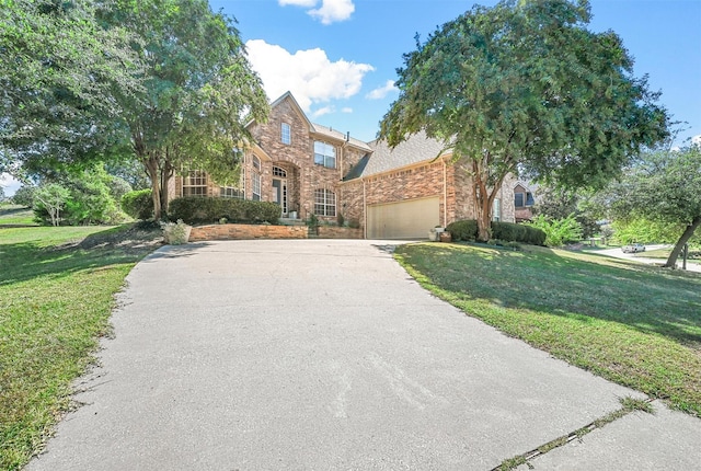 view of front of home with driveway, a garage, stone siding, a front lawn, and brick siding