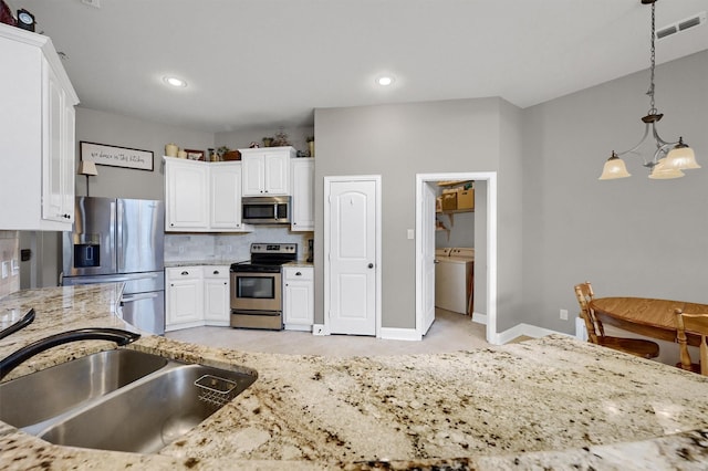 kitchen with a sink, visible vents, white cabinetry, appliances with stainless steel finishes, and backsplash