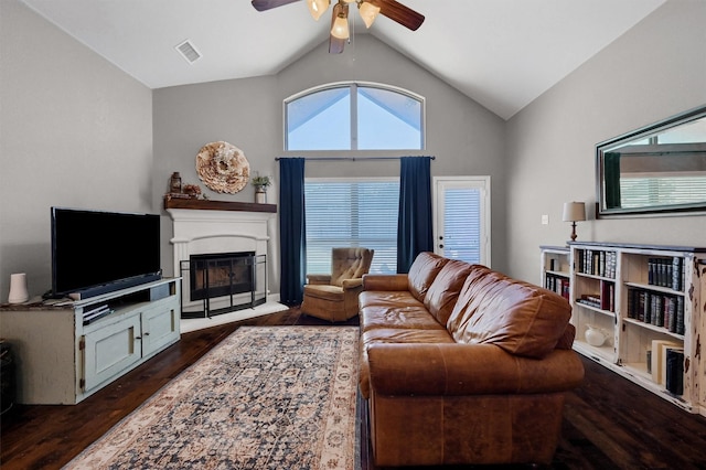 living room featuring lofted ceiling, ceiling fan, dark wood-style flooring, visible vents, and a glass covered fireplace