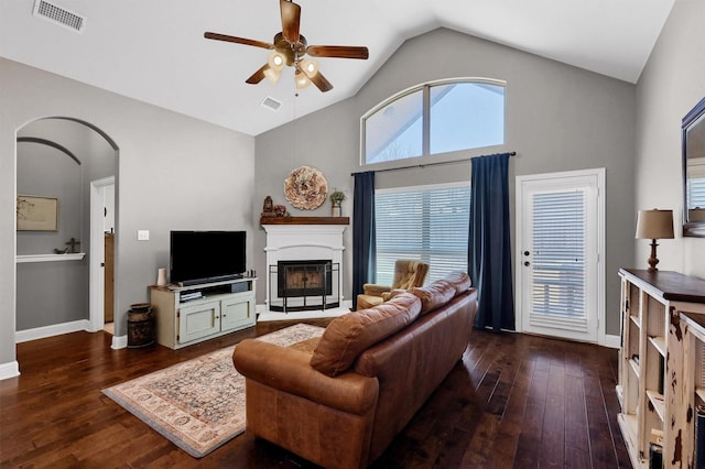 living room featuring arched walkways, visible vents, and dark wood finished floors