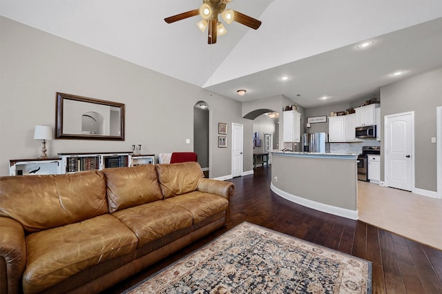 living room with arched walkways, baseboards, light wood-style flooring, ceiling fan, and high vaulted ceiling