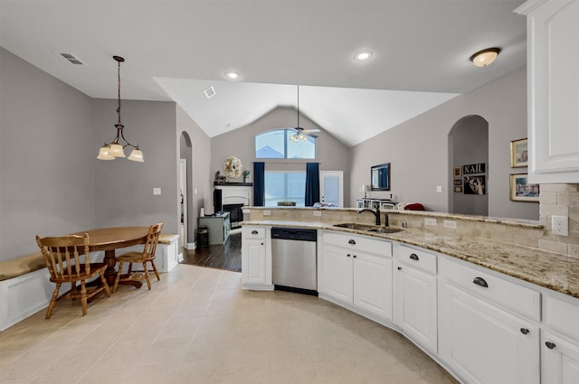 kitchen featuring visible vents, lofted ceiling, light stone counters, stainless steel dishwasher, and a sink