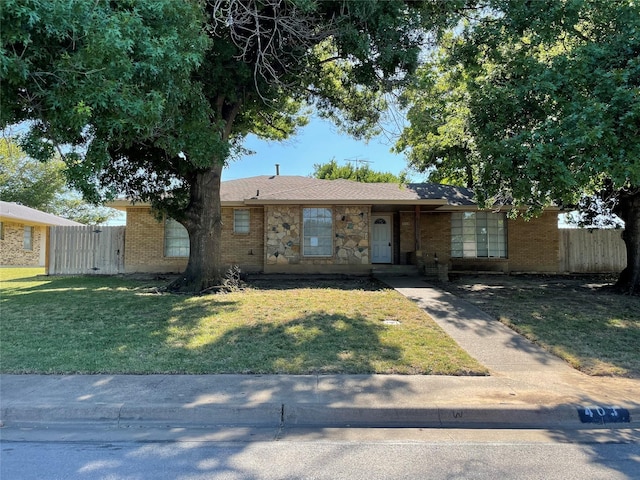 ranch-style house with brick siding, fence, and a front yard