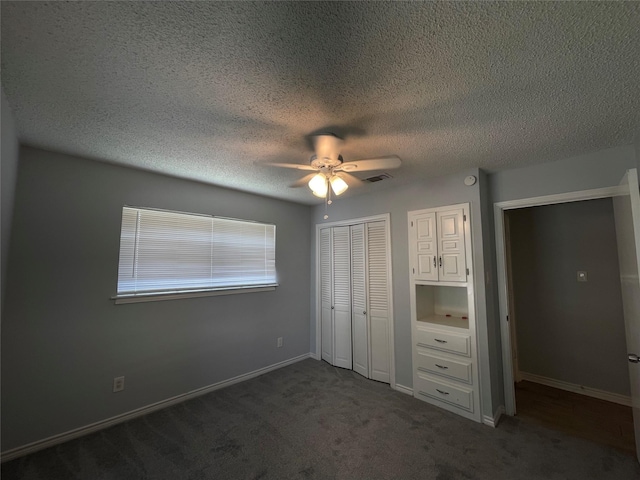 unfurnished bedroom with visible vents, baseboards, a ceiling fan, a textured ceiling, and dark carpet