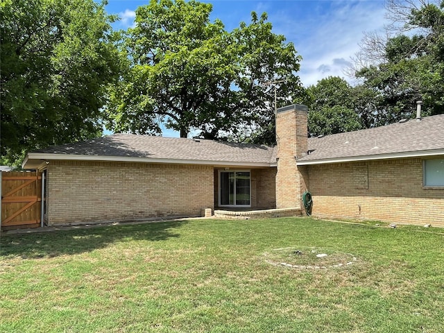 back of house featuring brick siding, fence, roof with shingles, a lawn, and a chimney