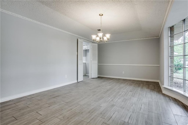 empty room featuring baseboards, ornamental molding, wood finished floors, a textured ceiling, and a chandelier