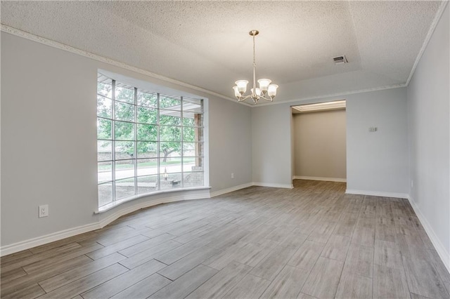 spare room with a textured ceiling, visible vents, ornamental molding, light wood-type flooring, and an inviting chandelier