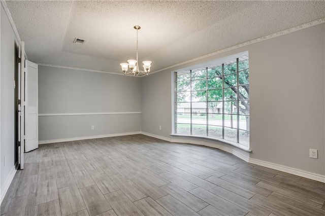 unfurnished room with a textured ceiling, wood finished floors, visible vents, and a notable chandelier