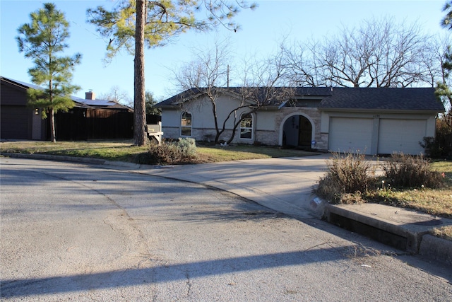 ranch-style house with driveway, stone siding, and an attached garage