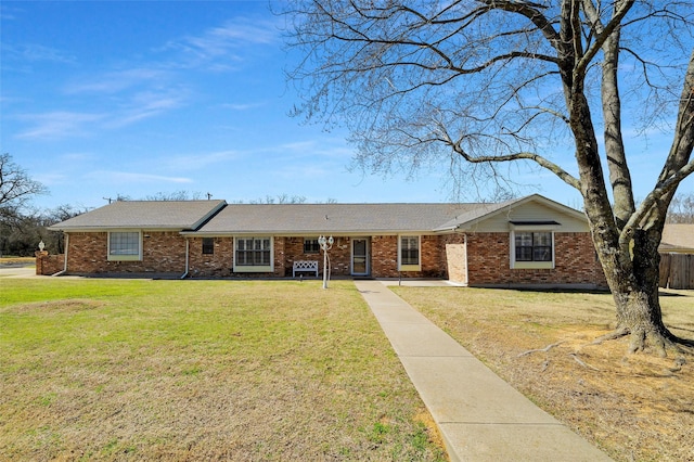 ranch-style house featuring brick siding, fence, and a front yard