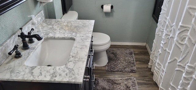 bathroom with wood finished floors, vanity, toilet, and baseboards