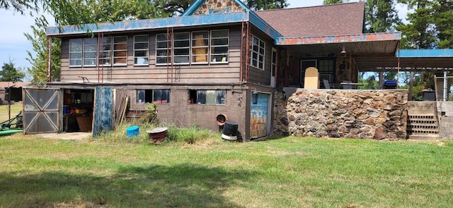 rear view of house featuring a shingled roof and a yard