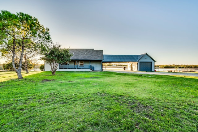 view of front facade featuring covered porch, a front lawn, and a detached garage