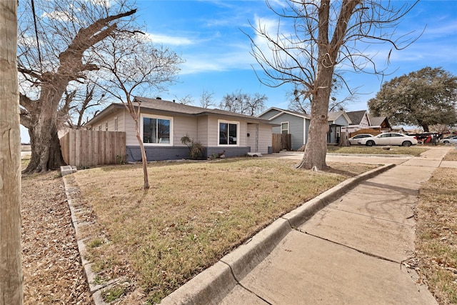 view of front of house with a front yard, brick siding, and fence