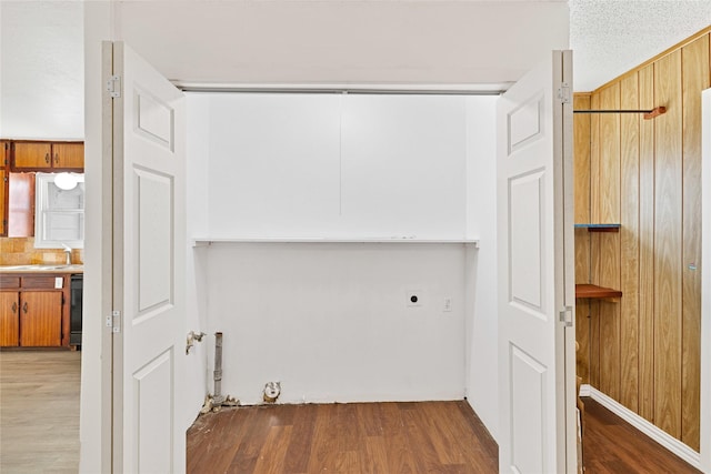 washroom featuring wood walls, laundry area, electric dryer hookup, and wood finished floors